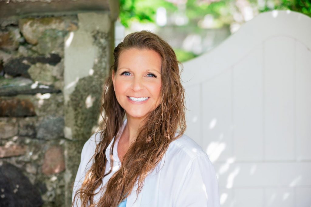 Nicole Bom smiling in front of white gate