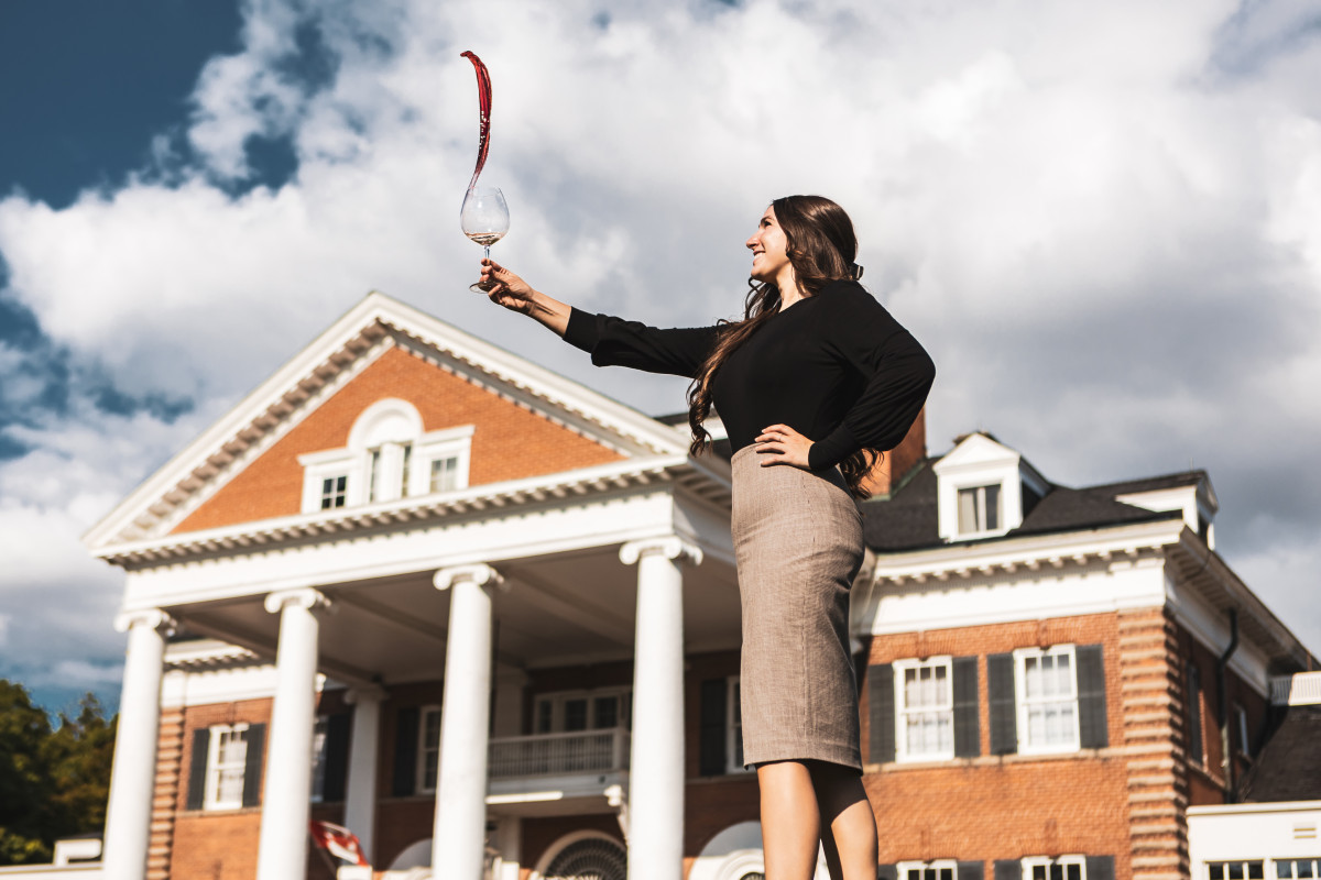 Esther holding up a glass of wine in front of Langdon Hall