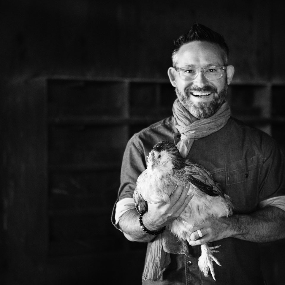 Executive Chef Jason Bangerter holding a hen with a wide smile