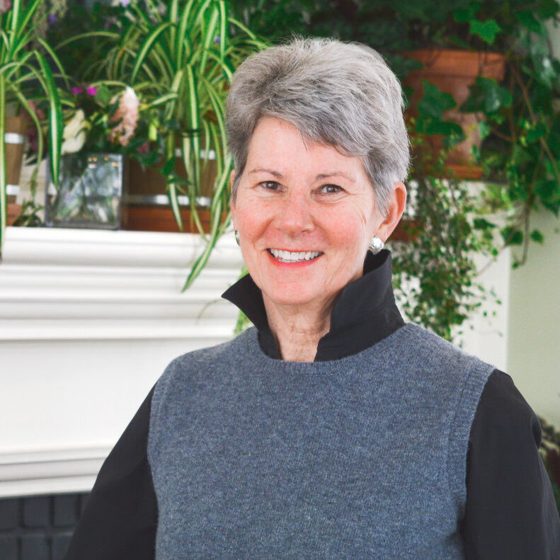 A headshot of Marion Anderson smiling in front of a fireplace mantel