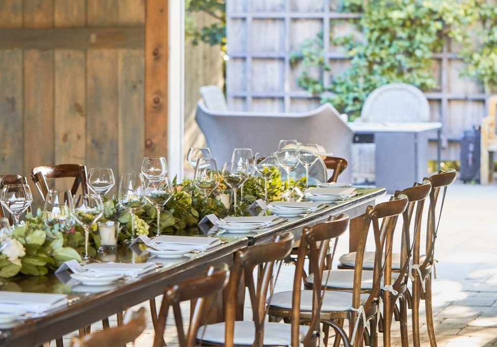 A harvest table prepared for dinner in an outside space