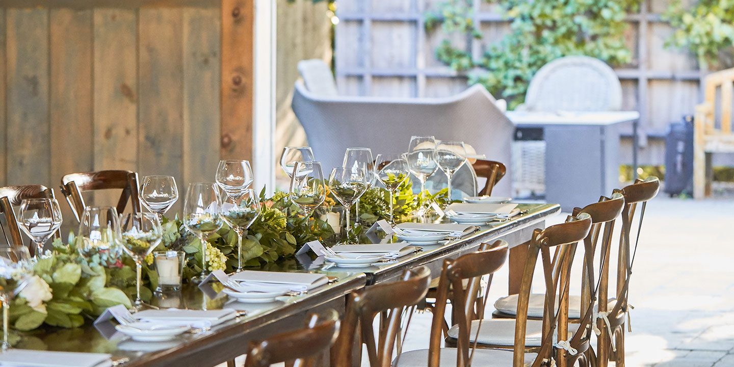 A harvest table prepared for dinner in an outside space